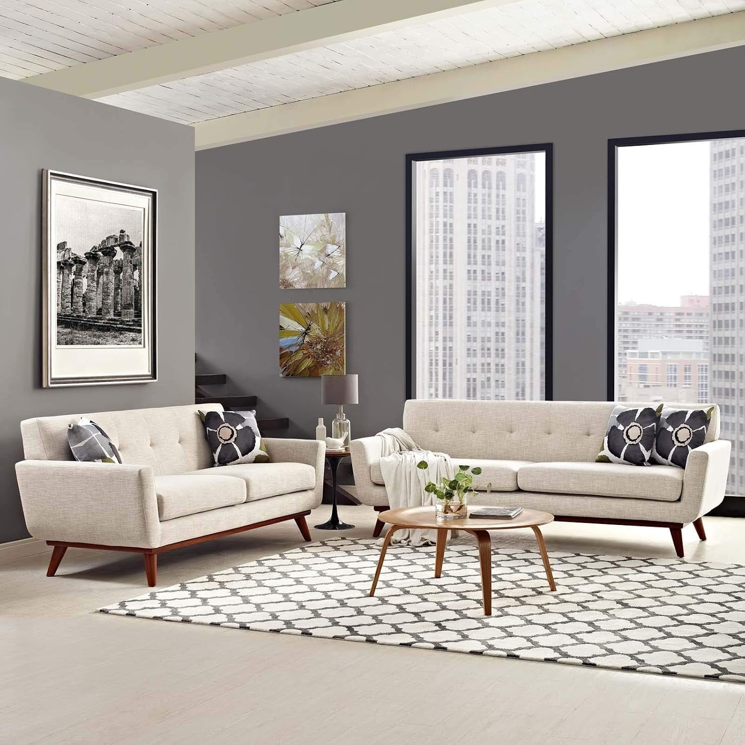 Wide living-room scene with two light sofas facing a round wood coffee table beneath tall city-view windows
