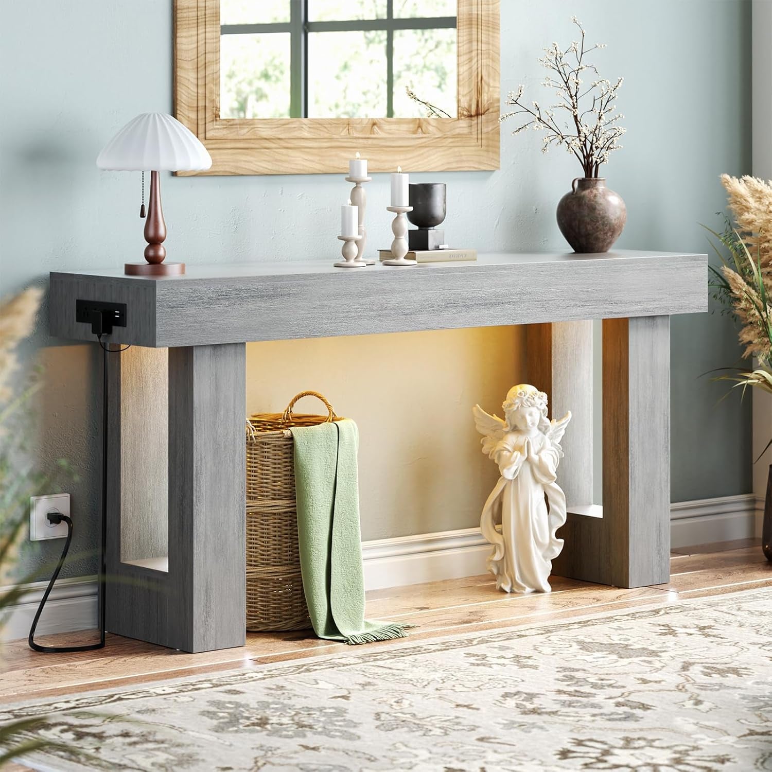 Light-gray console table against a pale wall with mirror above, lamp and candlesticks on top, under-shelf light on