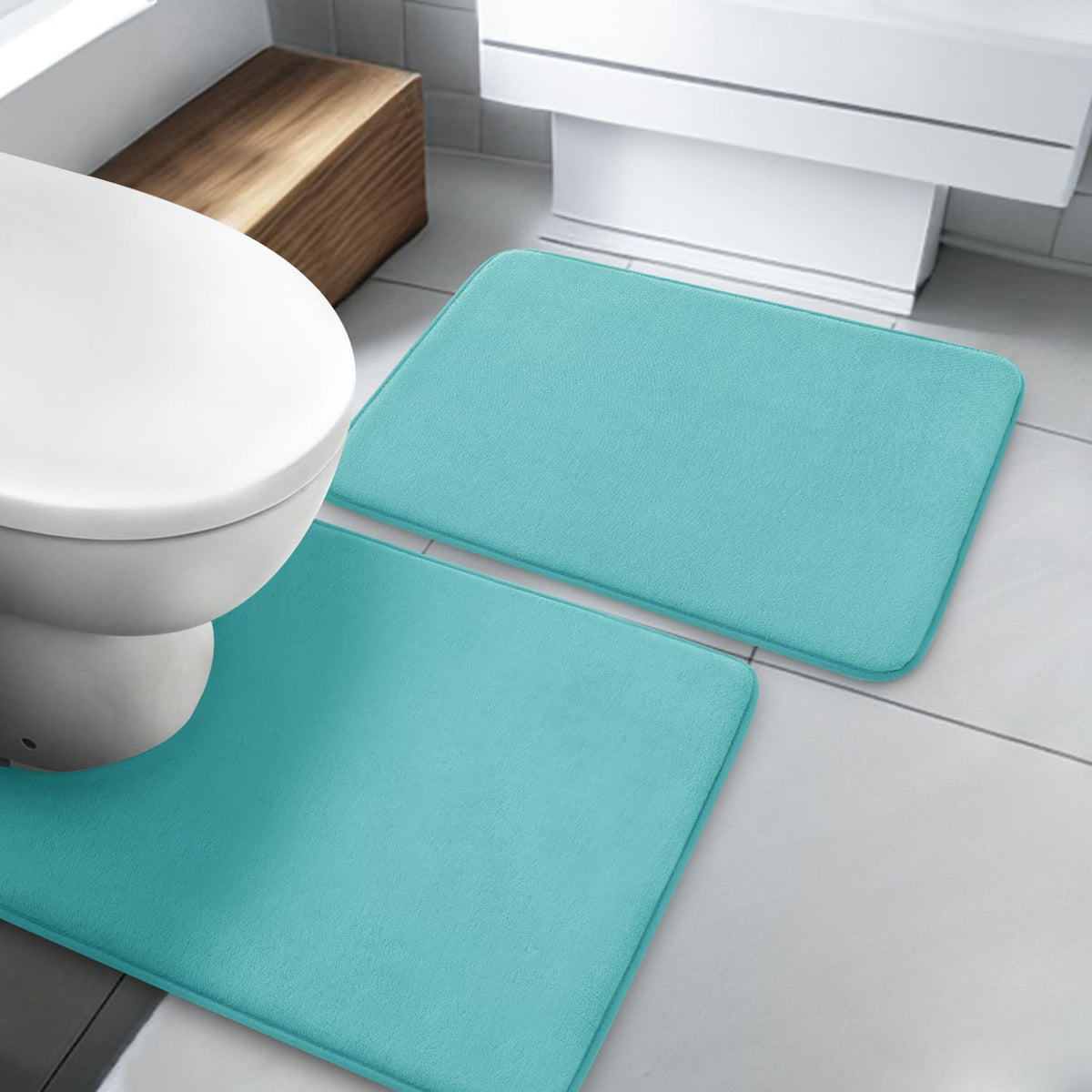 Overhead angle showing three dark gray memory-foam bath rugs arranged around a toilet and cabinet.