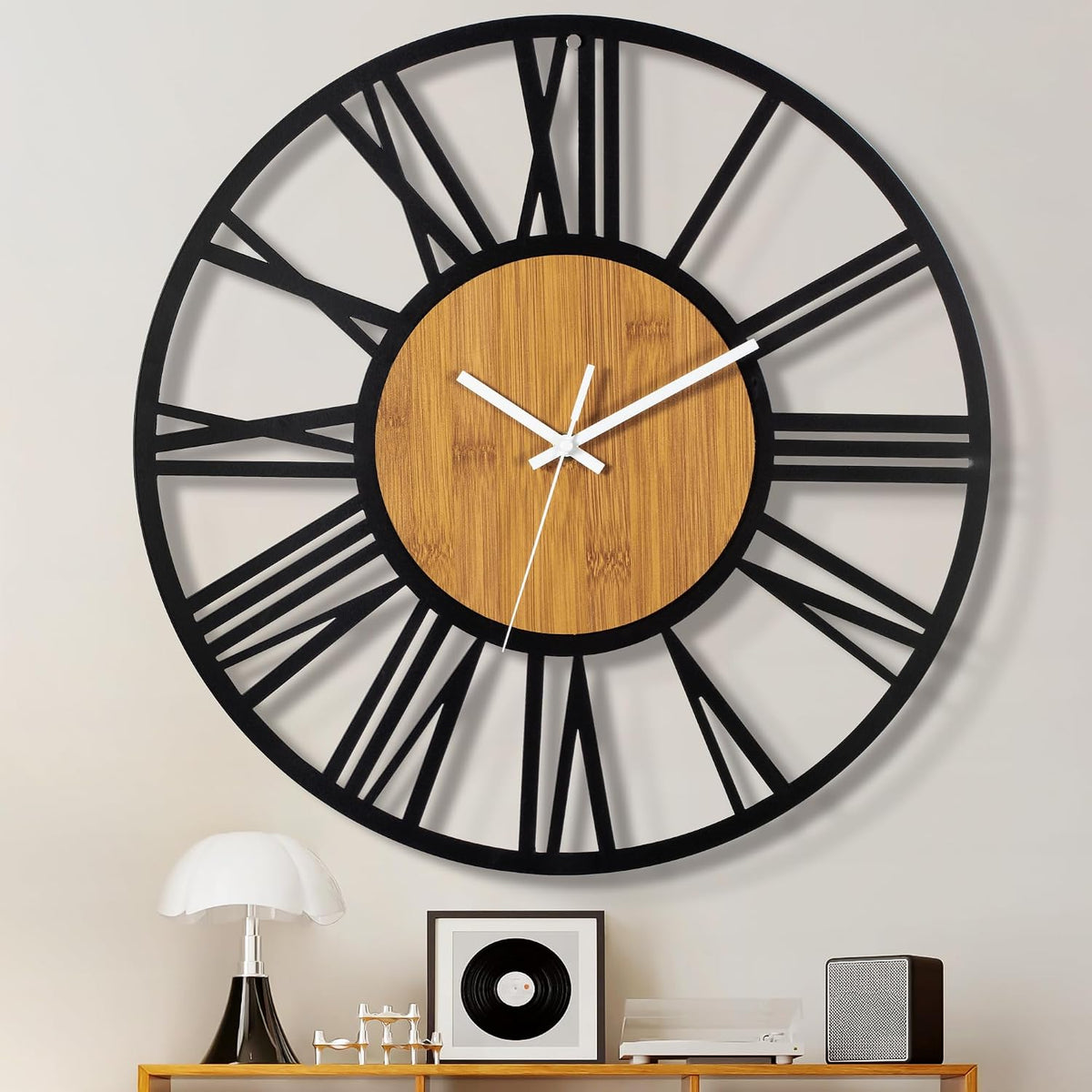 Large black metal and wood clock hanging above a console with lamp, framed art and audio speaker