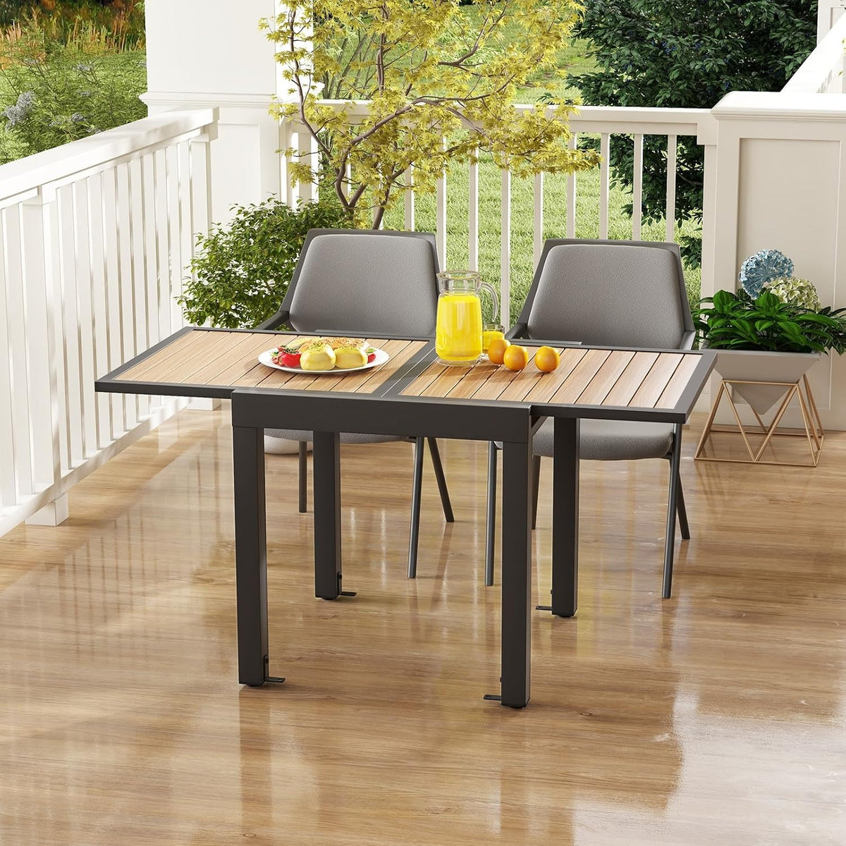 Porch view of the dark gray table partly extended with two gray chairs and a pitcher on top.