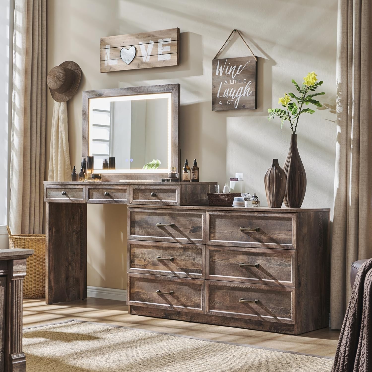Rustic wooden vanity with matching nine-drawer dresser, lighted square mirror, vases and toiletries in a sunlit bedroom