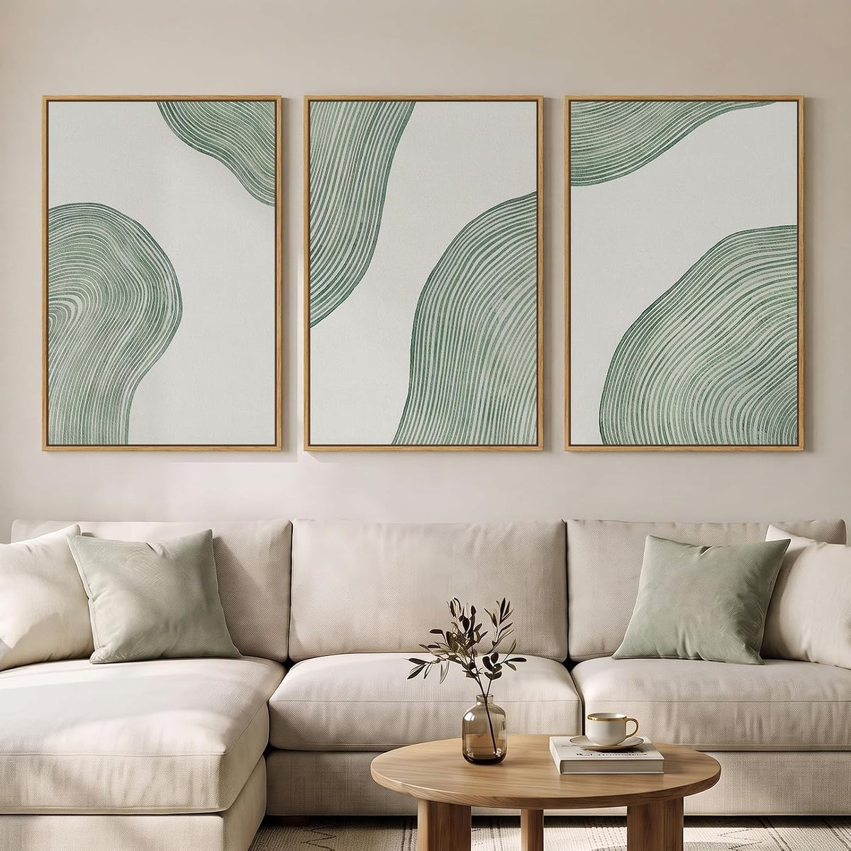 Three vertical minimalist prints with sage-green concentric line shapes above a cream sectional.