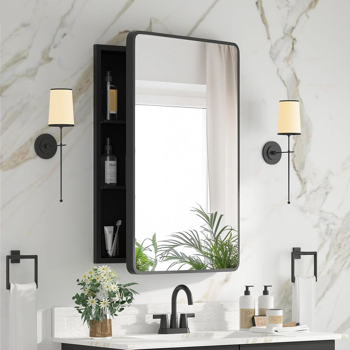 Black-framed wall mirror cabinet with open left shelving, mirror reflecting window and plants above a black faucet.