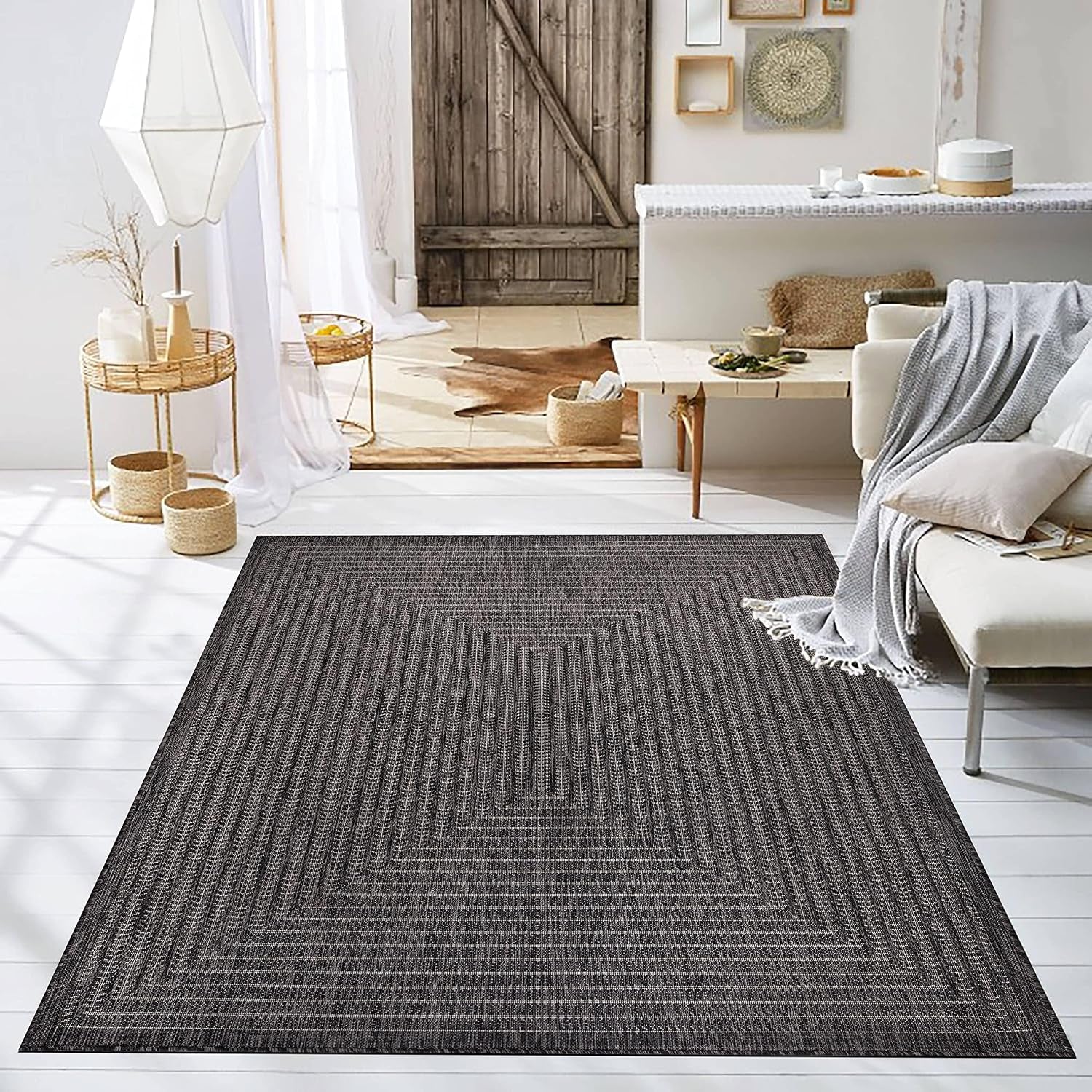 Dark-gray area rug centered in a bright living room with sofa, throw and rustic door backdrop
