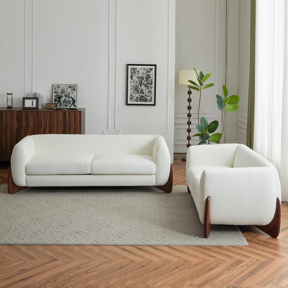 White bouclé sofa and loveseat arranged in a bright room view showing rounded silhouette and tapered birch legs
