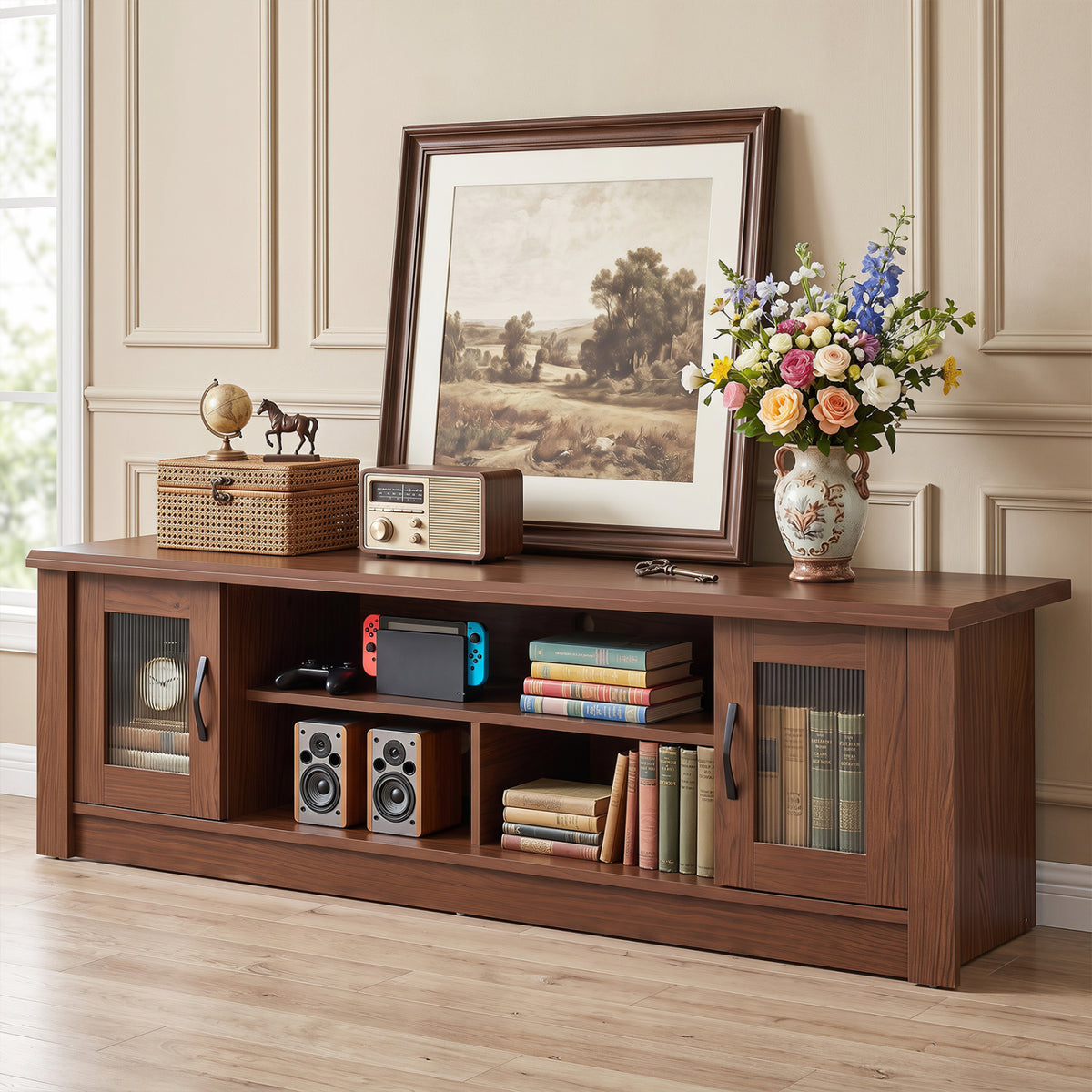 Brown wooden TV stand styled with books, speakers, a game console, framed art, and flowers.