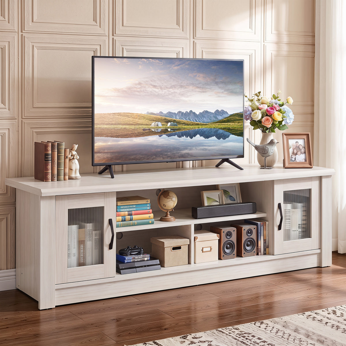 White wood-grain TV stand with fluted doors and open shelves beneath a television in a paneled living room.