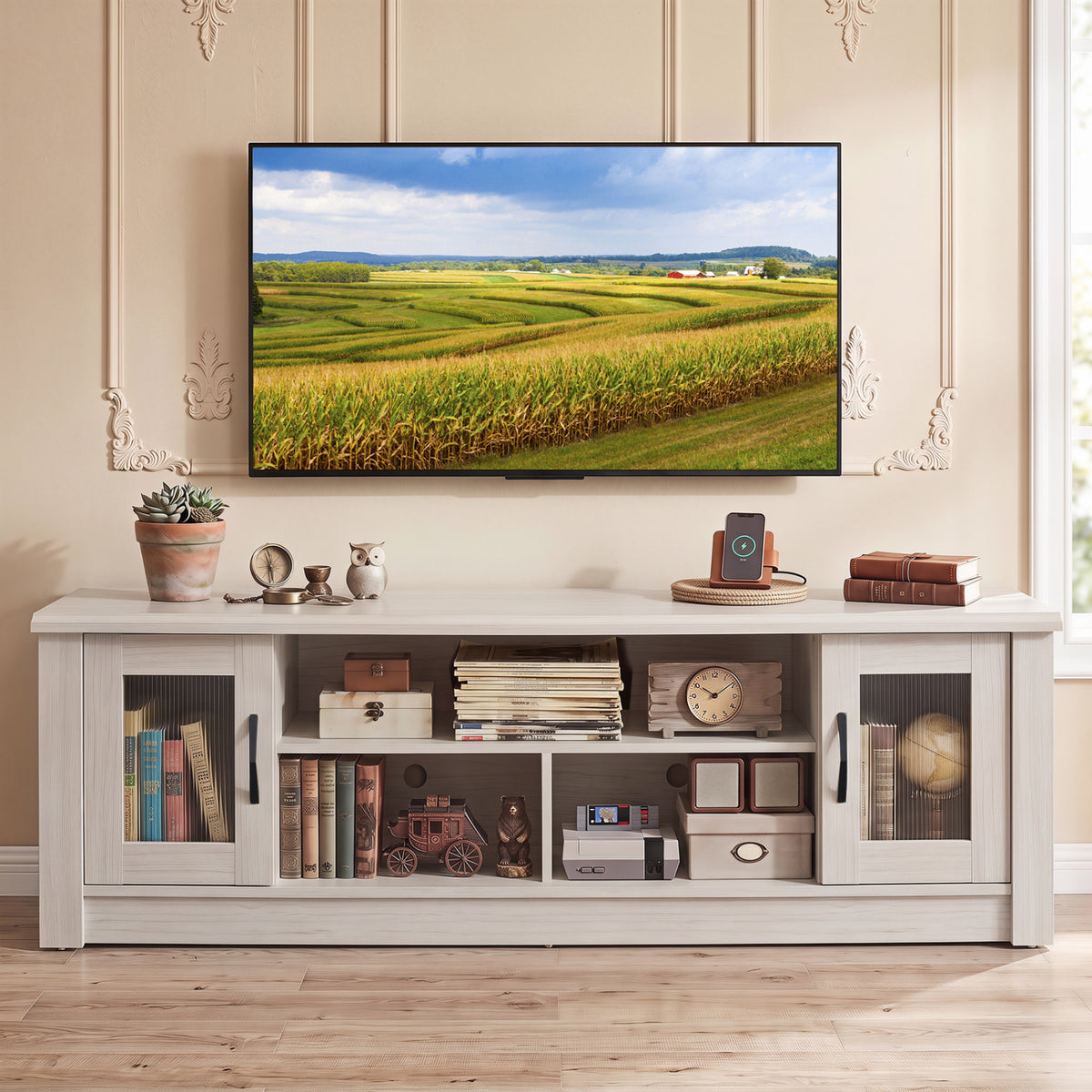 Front view of the light wood TV stand styled with books and decor beneath a wall-mounted television.