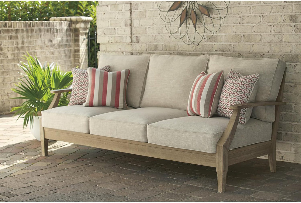 Beige three-seat outdoor sofa front view with beige cushions and patterned throw pillows on a brick patio