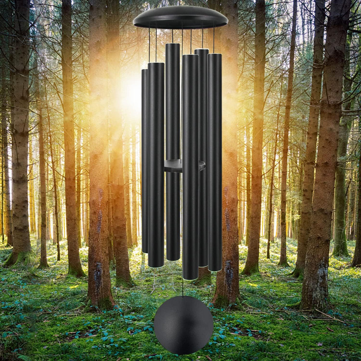 Tight view of dark metal chimes and round wind sail against backlit trees in a forest setting.