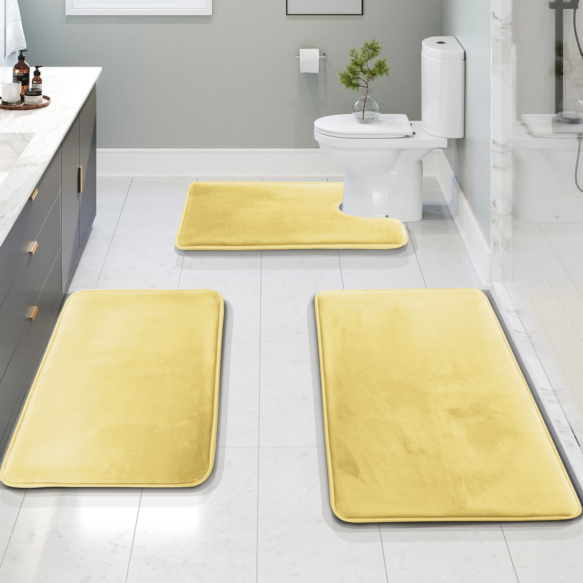 Bathroom scene with three yellow memory-foam rugs, including a U-shaped piece placed around the toilet.
