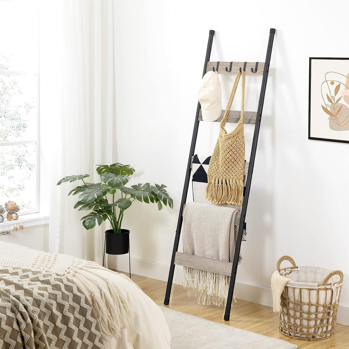 Ladder in a bedroom scene with folded blankets draped across the greige slats and black side rails