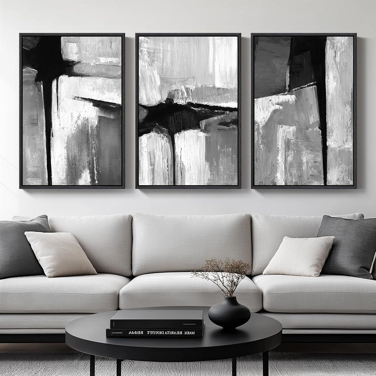 Three black-and-white textured abstract panels in black frames mounted above a light sofa and round coffee table.
