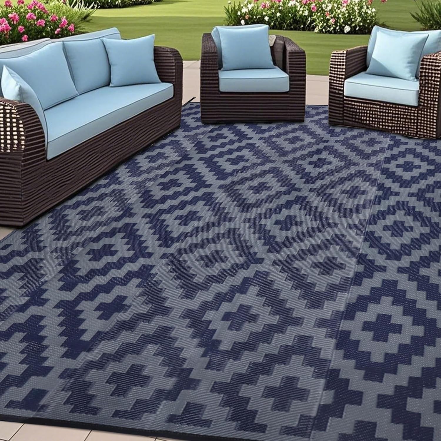 Outdoor seating set on a blue-gray and navy geometric outdoor rug in a garden setting.