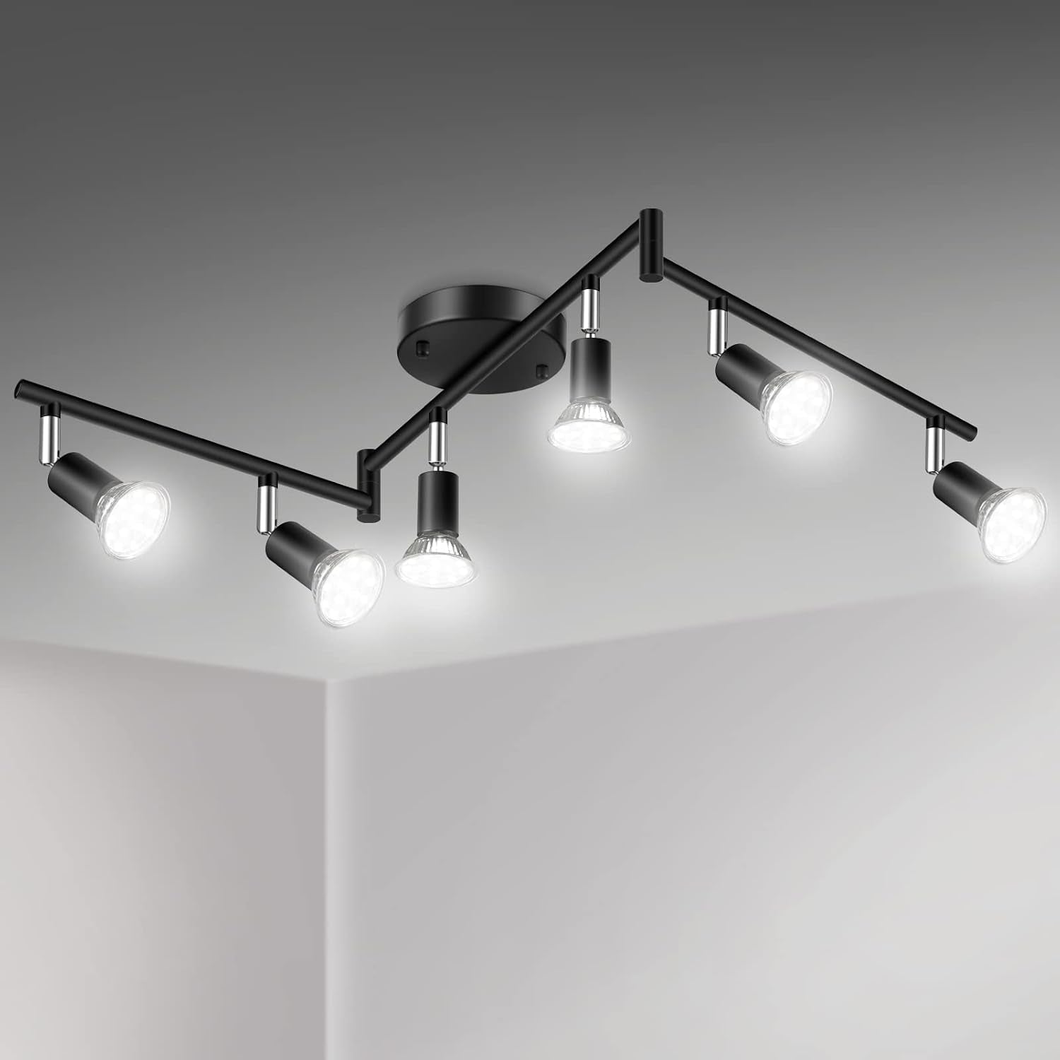 Ceiling-mounted six-light track fixture in matte black with all heads lit over a corner ceiling.