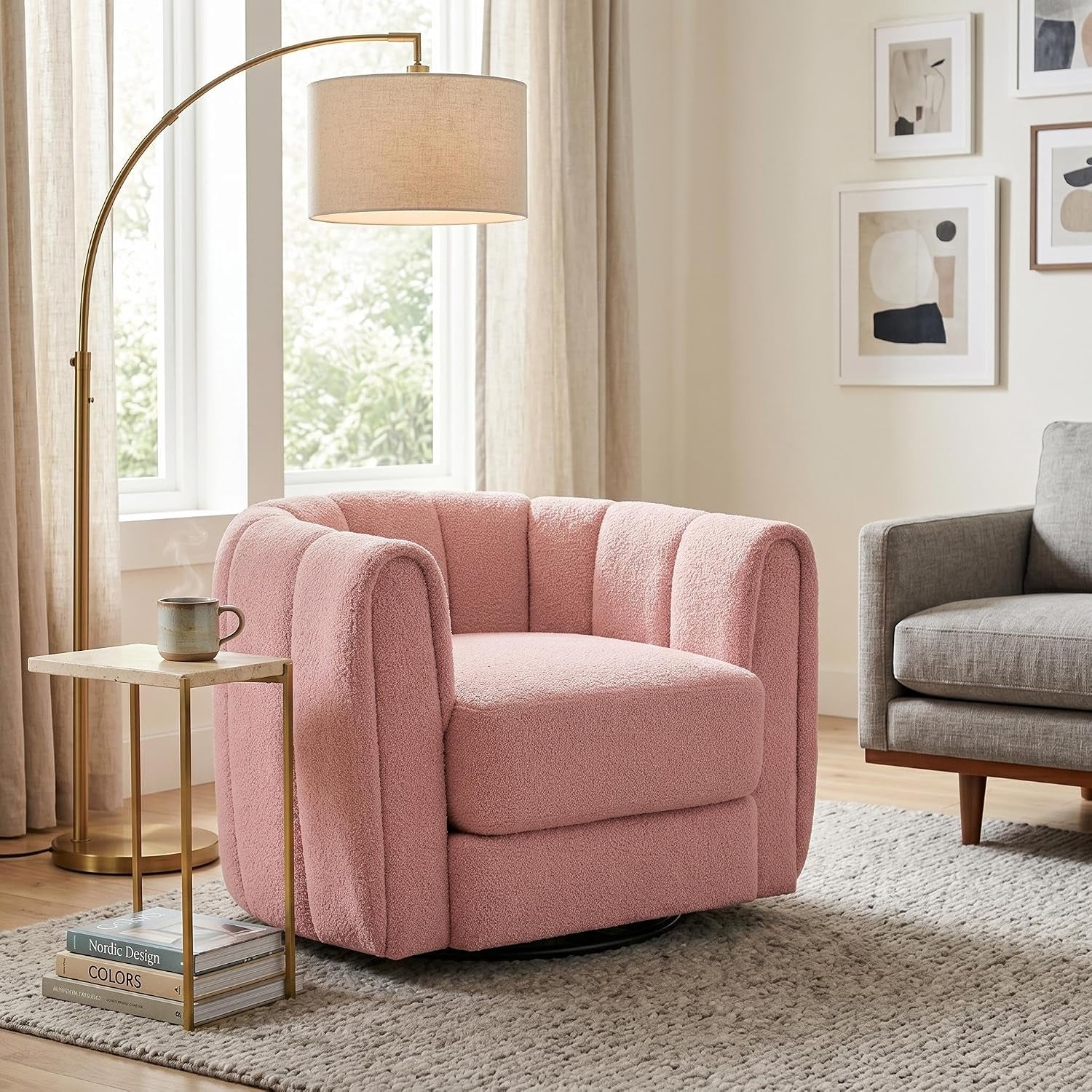 Single pink teddy-fleece swivel barrel chair beside a slim gold side table and arc floor lamp.
