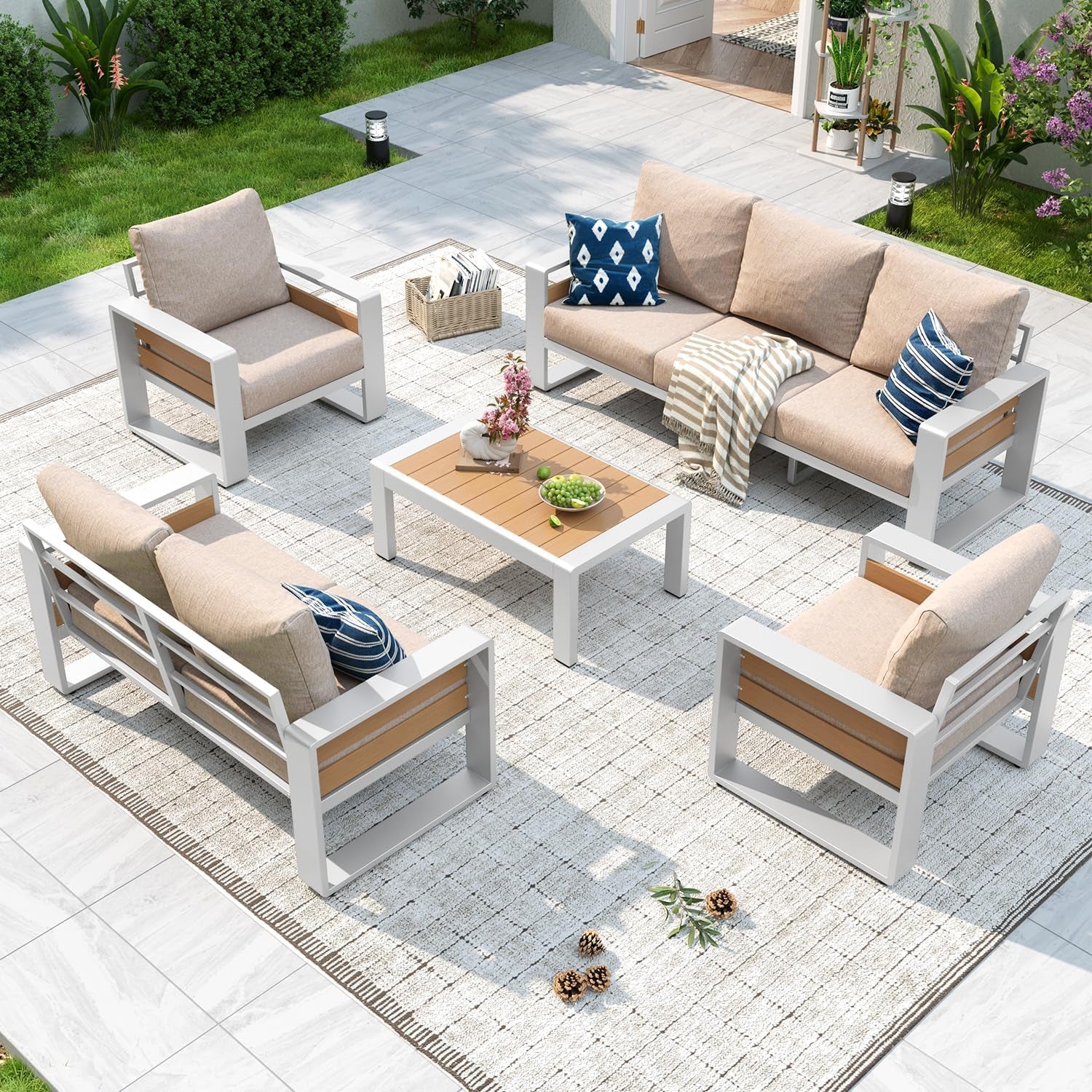 Outdoor sectional with beige cushions and white frames around a low wood-top coffee table on a light patio rug.