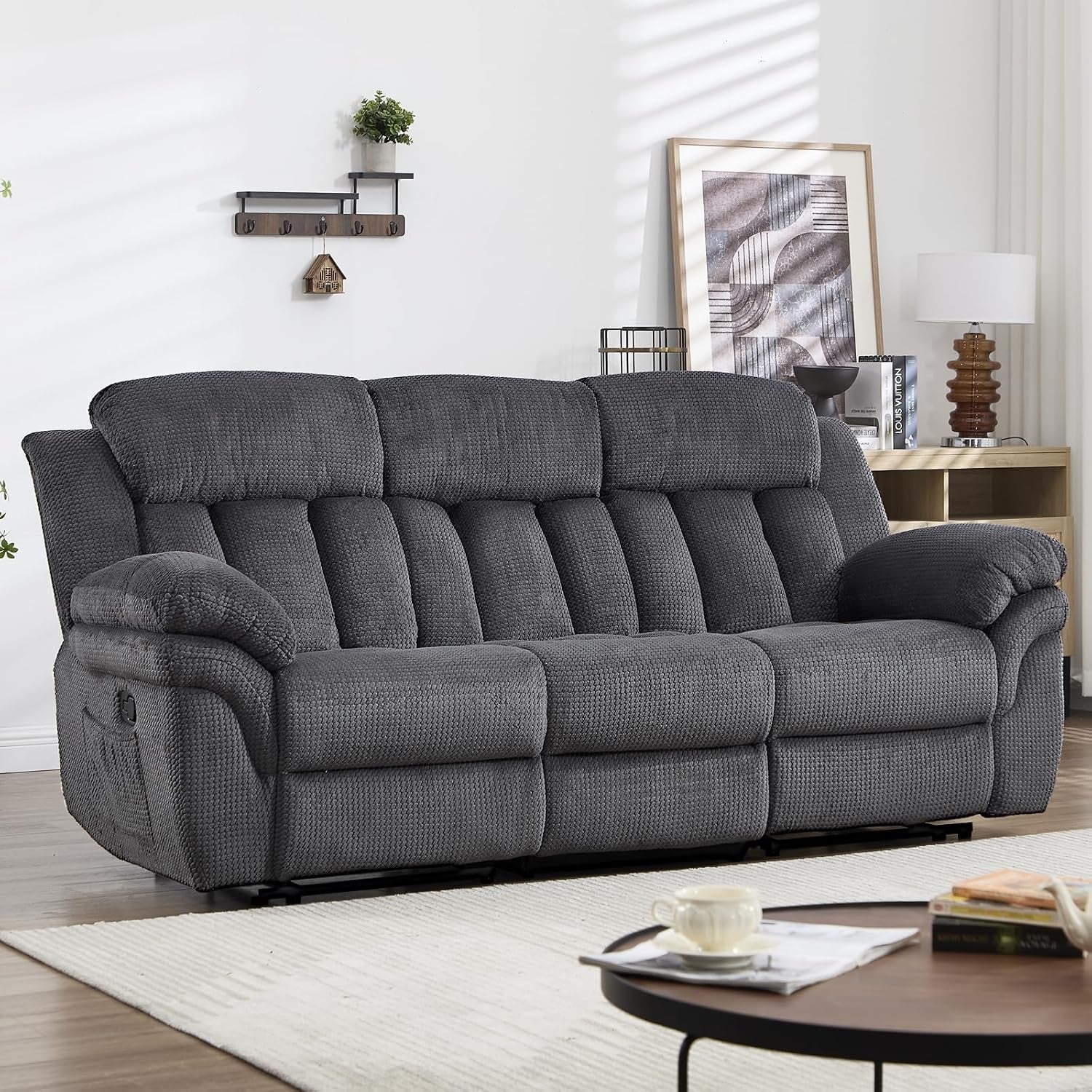 Cropped front view of a three-seat reclining sofa with padded arms and segmented tufted back cushions.