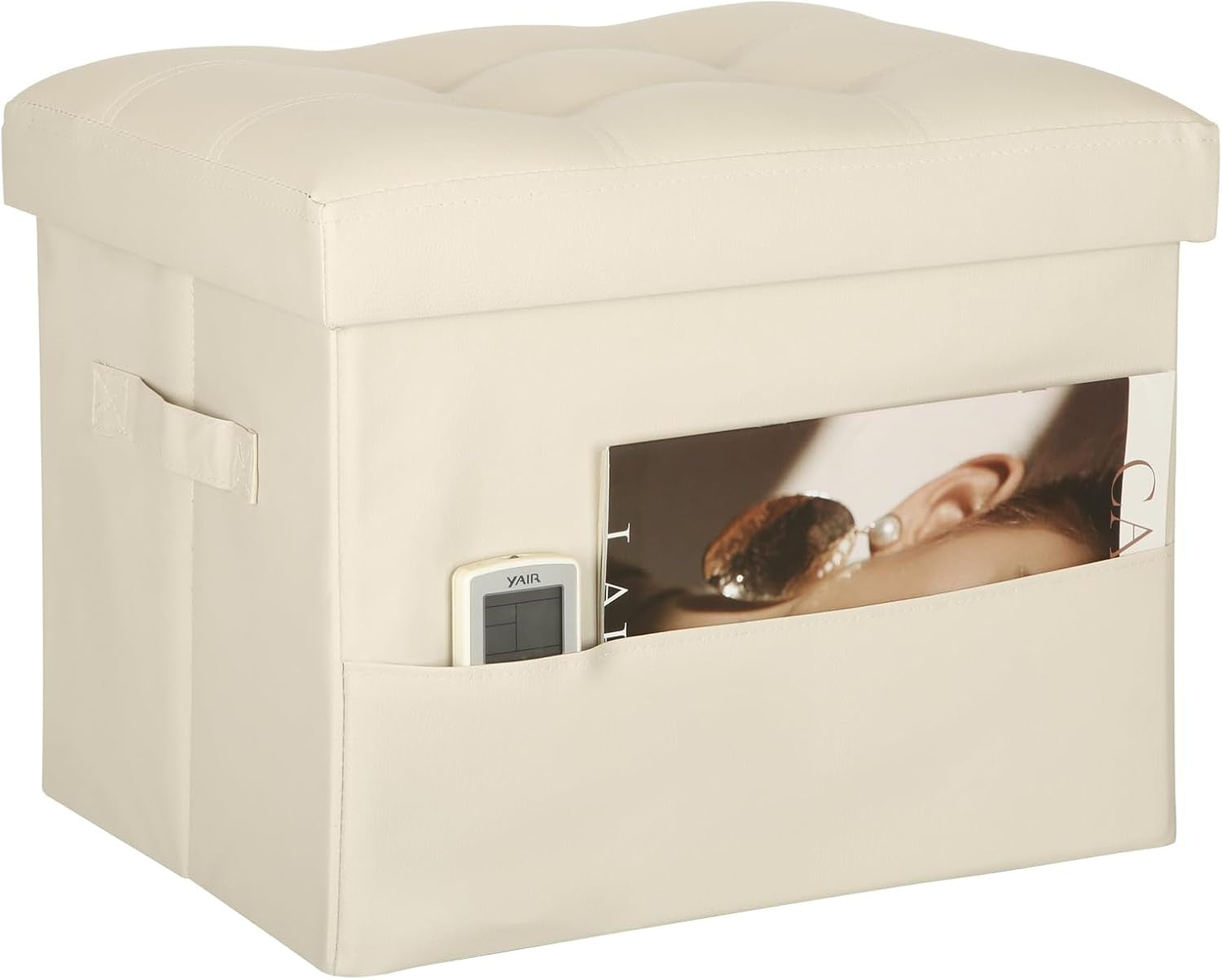 Cream faux-leather storage ottoman with tufted lid and front pocket holding a magazine and a remote.
