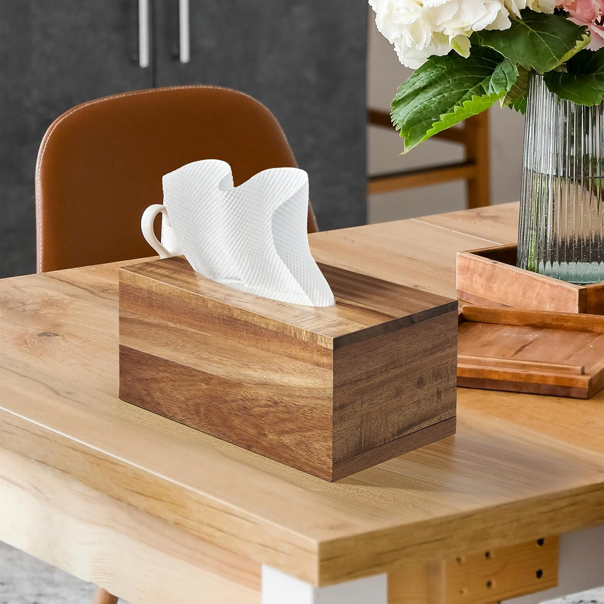 Acacia-finish rectangular tissue box cover on a dining table with a vase of flowers and chair in the background