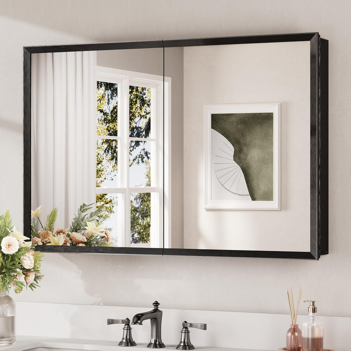 Black two-door mirrored medicine cabinet mounted above a bathroom sink reflecting a window and wall art.