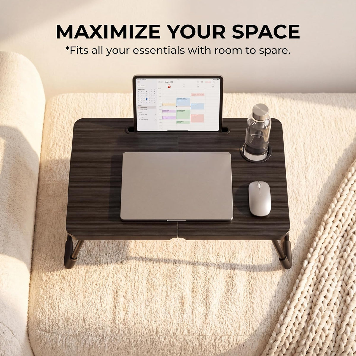 Overhead view of black lap desk on a light rug with tablet in groove, laptop and mouse on the surface