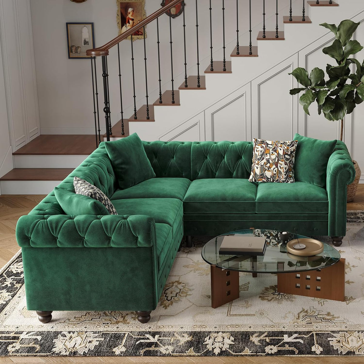 Green velvet L-shaped sectional under a staircase in a living entry, with patterned pillows and a fiddle‑leaf fig.