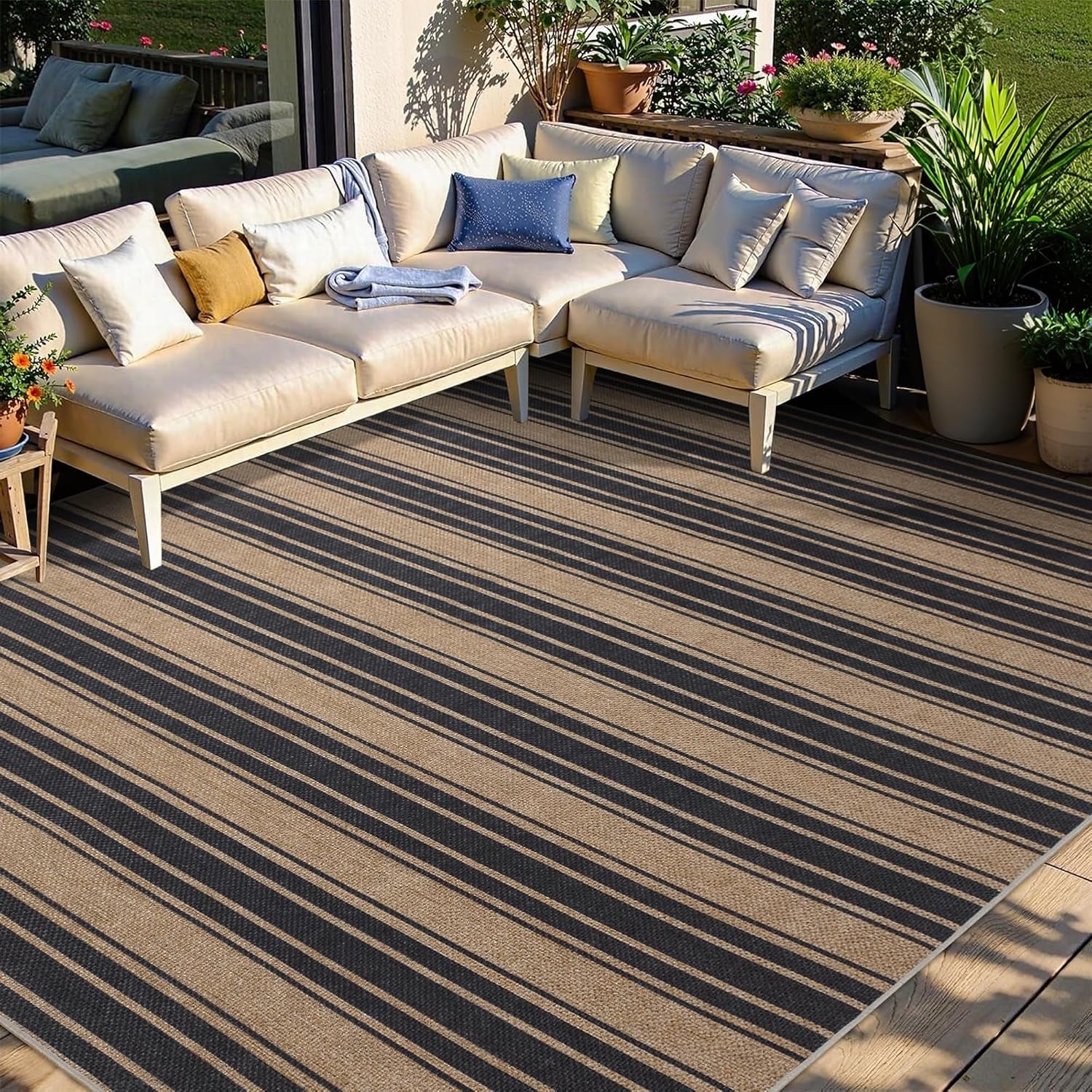 Outdoor sectional sofa arranged on a striped rug with potted plants and sunlight casting shadows