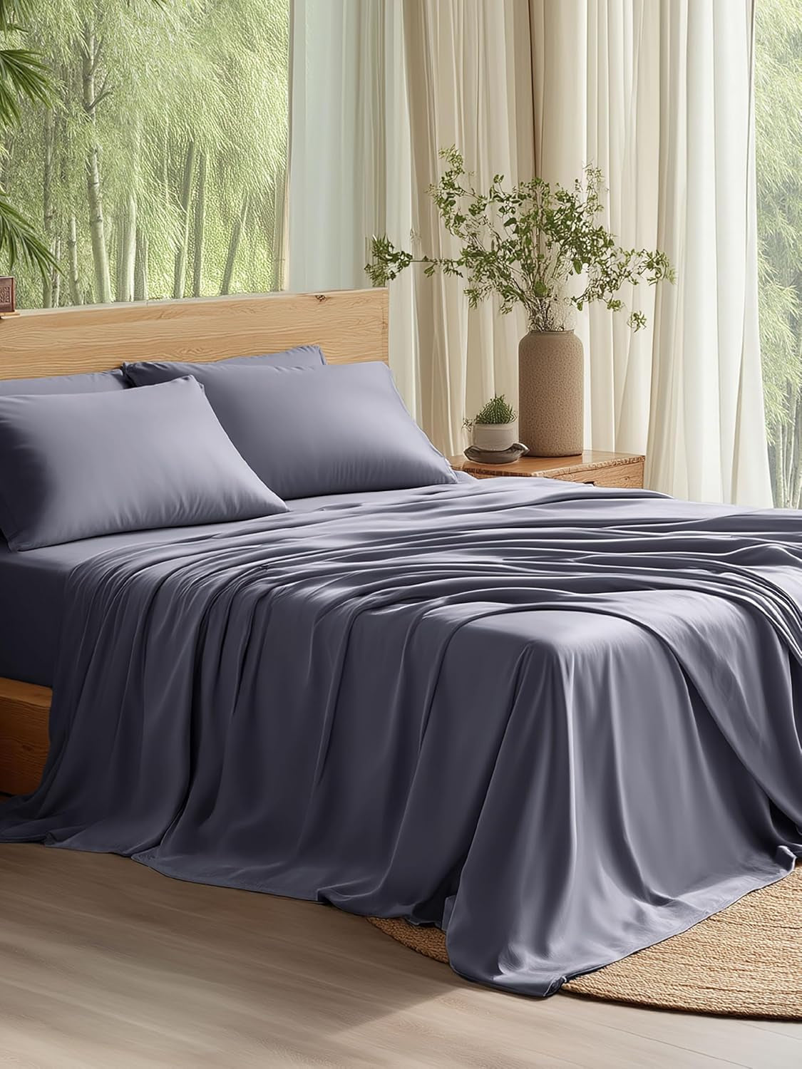 Made bed with smooth lavender-gray sheets, two pillows, wood headboard and a vase on the nightstand by sheer curtains.