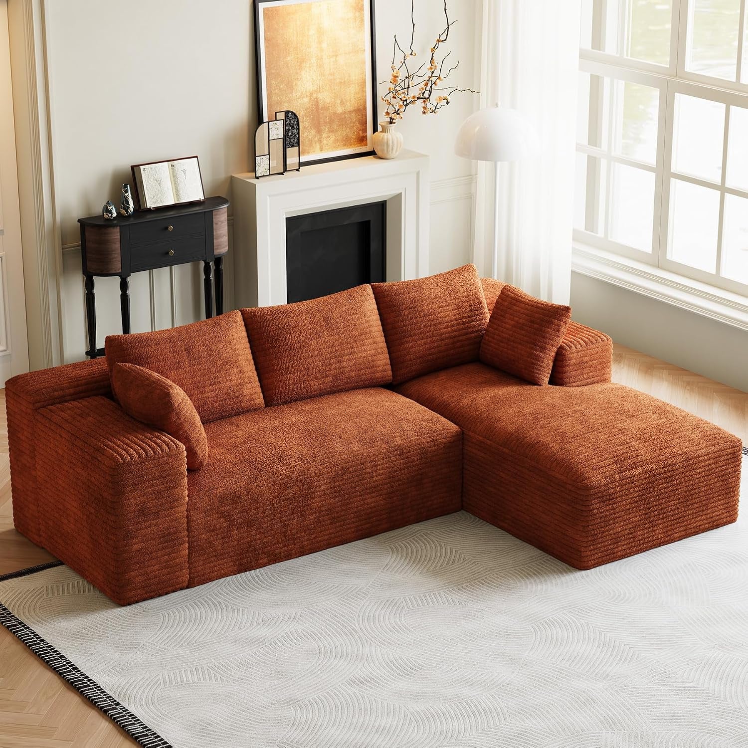 Rust-colored L-shaped sectional with chaise set near a fireplace and large window