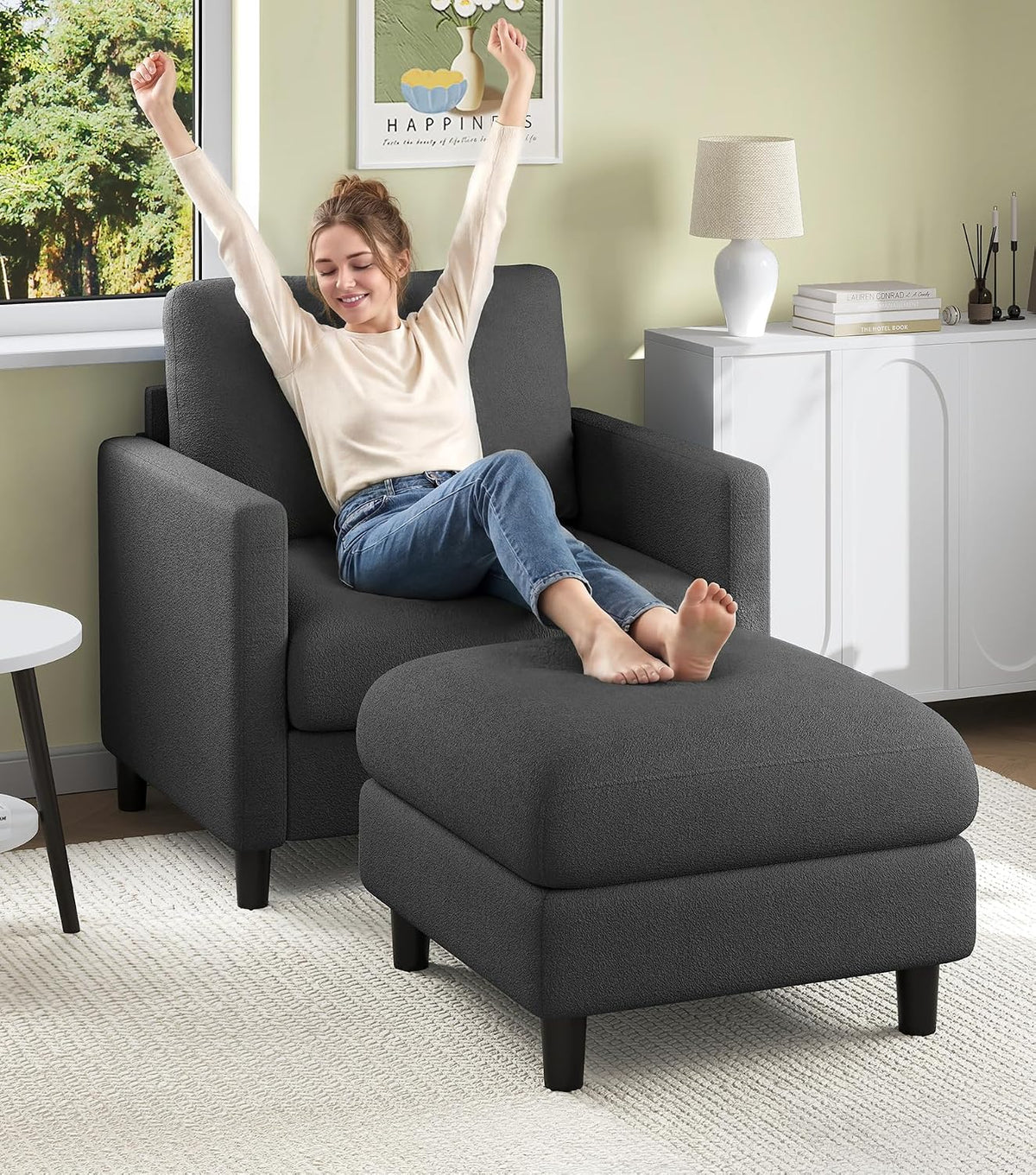 Dark gray loveseat with matching ottoman; woman reclining with feet on the ottoman.