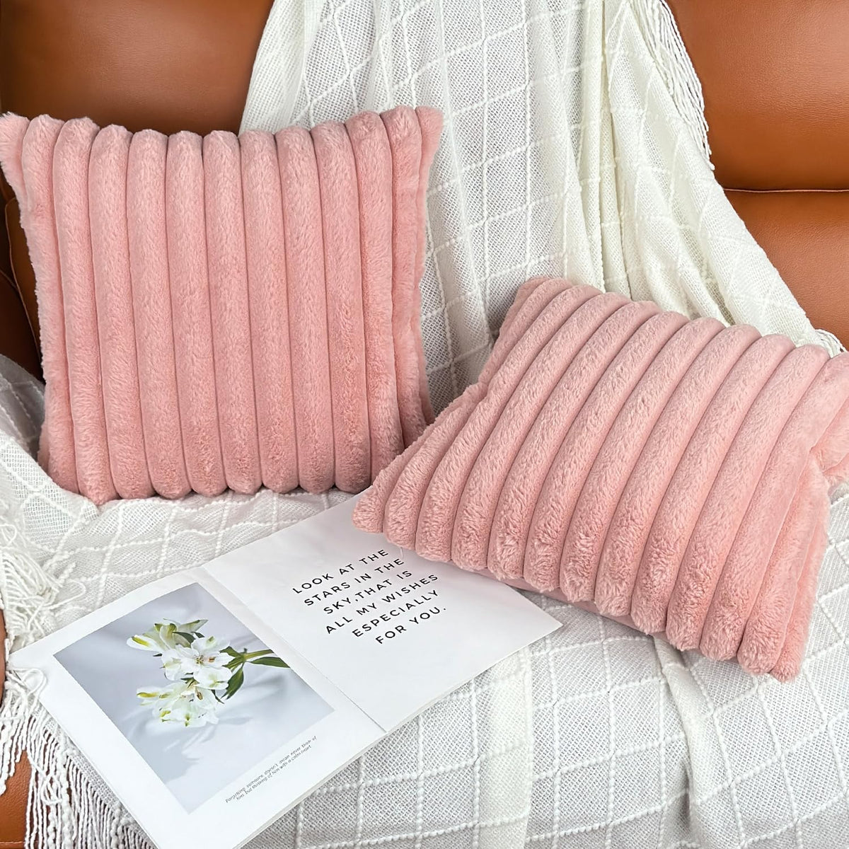 Two pink ribbed pillows arranged on a white textured blanket on a sofa