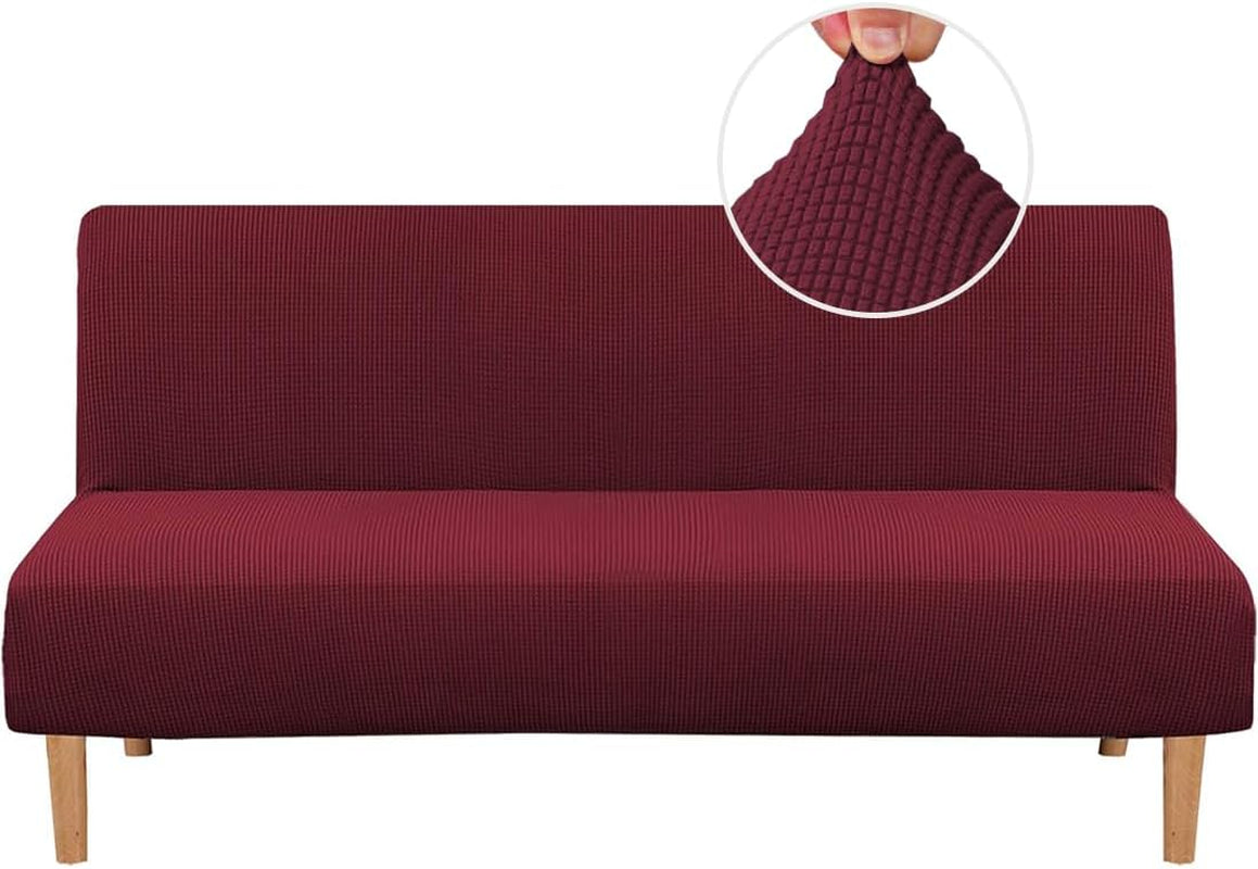 Front view of a armless futon covered in a textured burgundy stretch slipcover with wood legs.