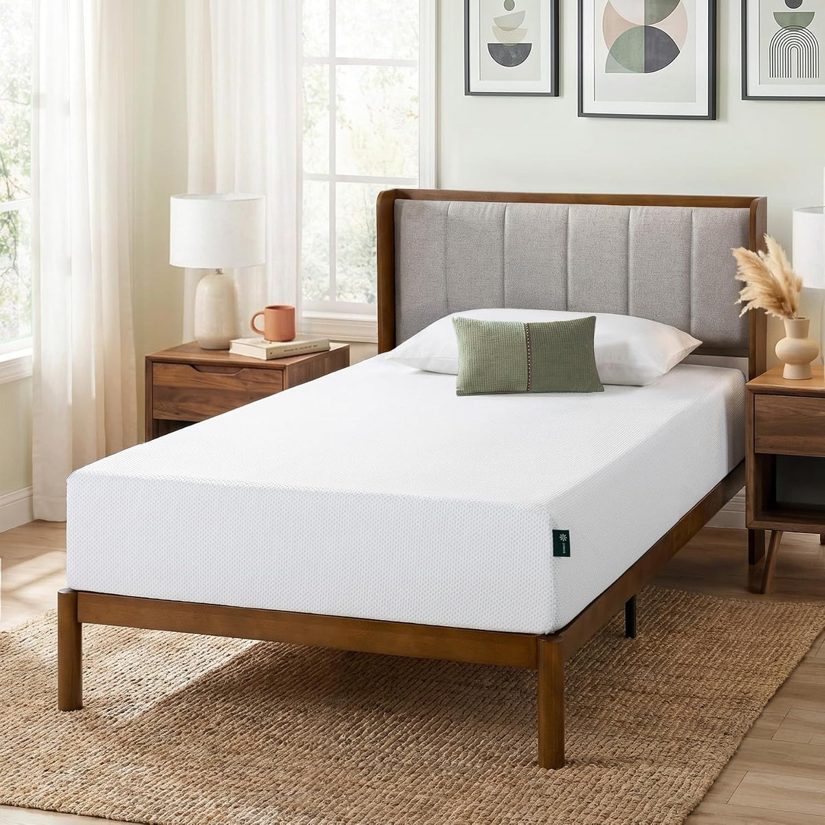 Angled side view of the mattress on a wooden frame highlighting its height and textured white cover in a styled bedroom.