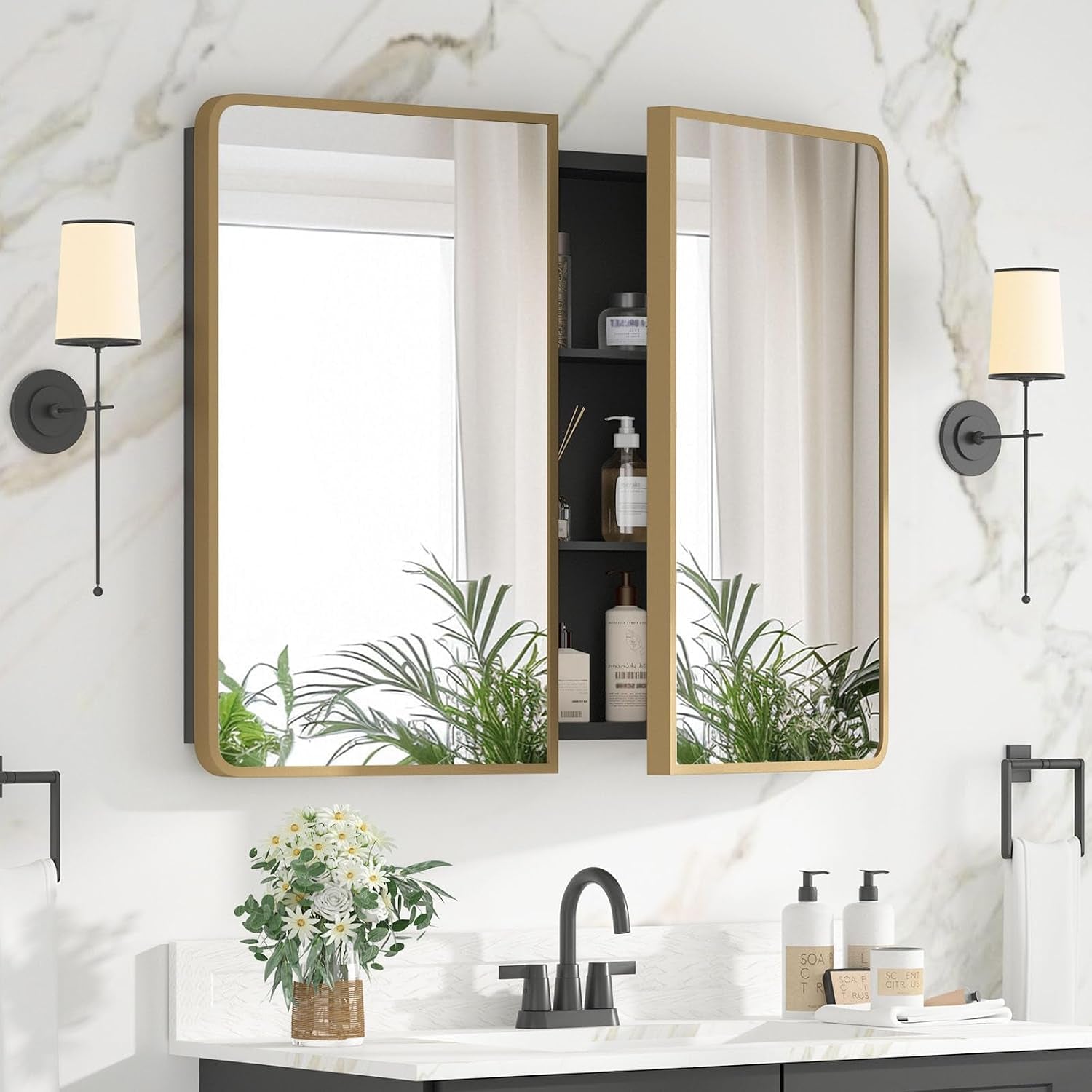 Wall-mounted gold-framed mirrored medicine cabinet above a sink, one door open revealing dark interior shelves and bathroom