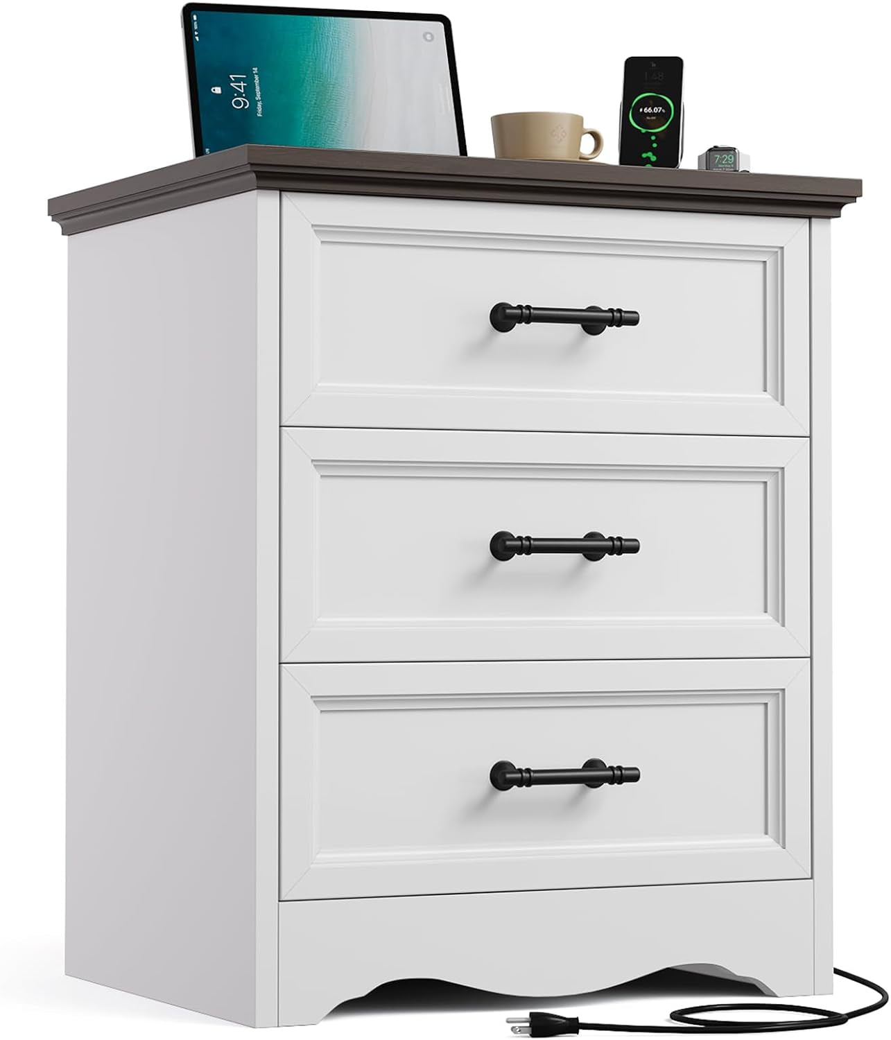 Front view of a white three-drawer nightstand with a dark brown top, black handles and items on top.