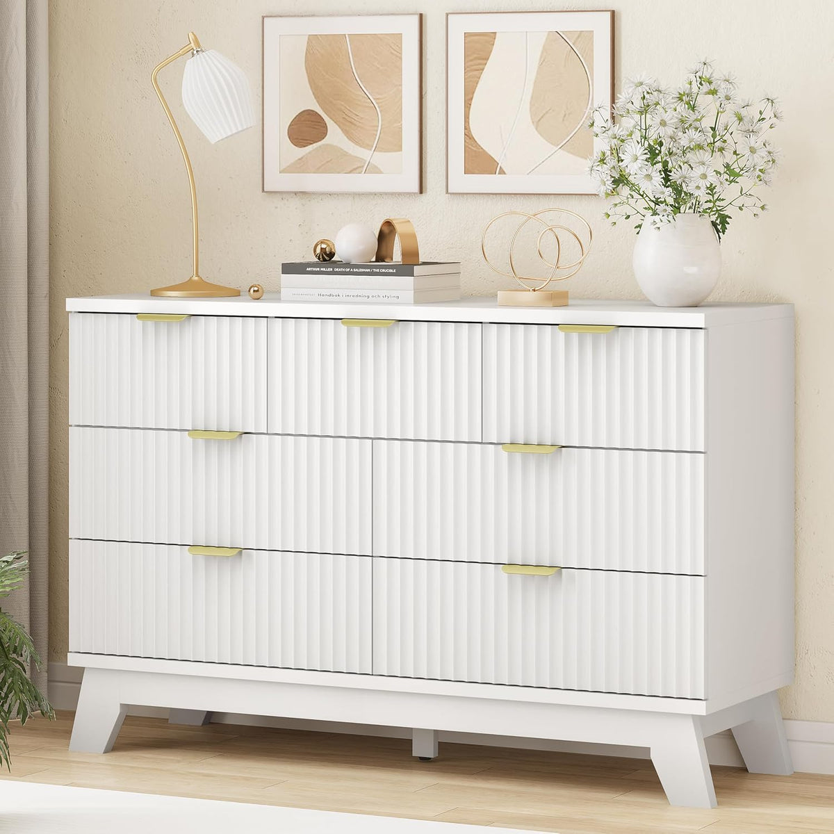 Cropped close-up of the white dresser top with lamp, books and decorative vase over ribbed drawers