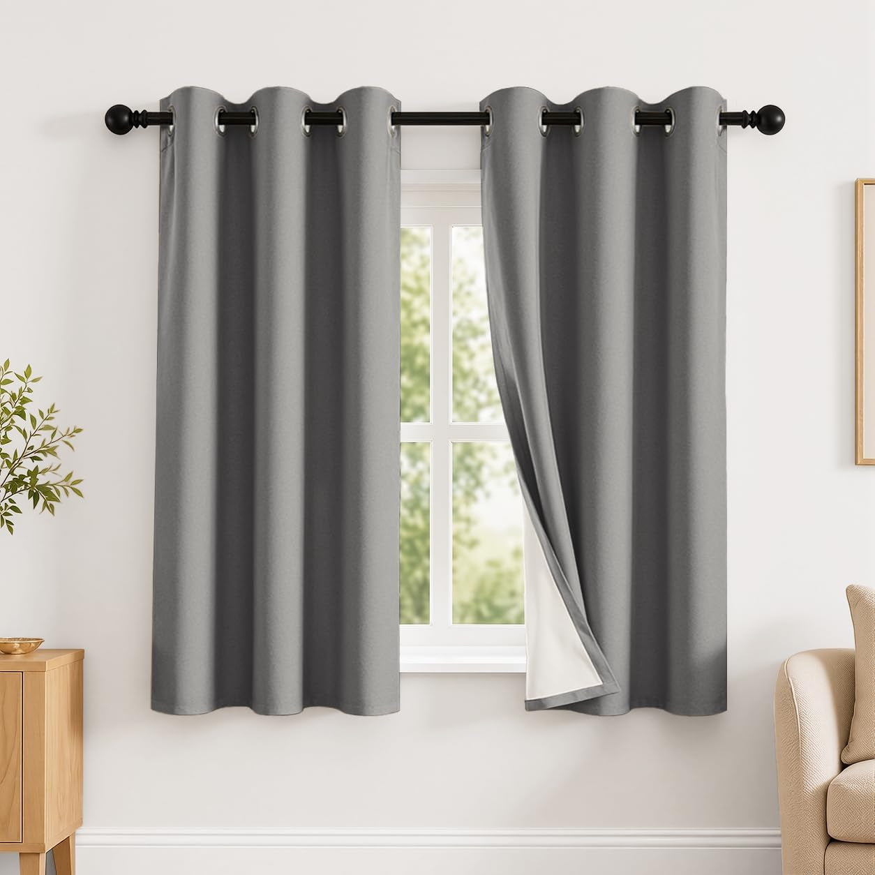 Single window with medium gray grommet curtains, one panel pulled open to reveal white backing