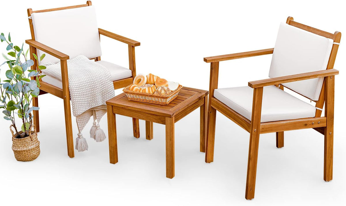 Two acacia wood armchairs with white zippered cushions and tie straps flanking a slatted acacia coffee table