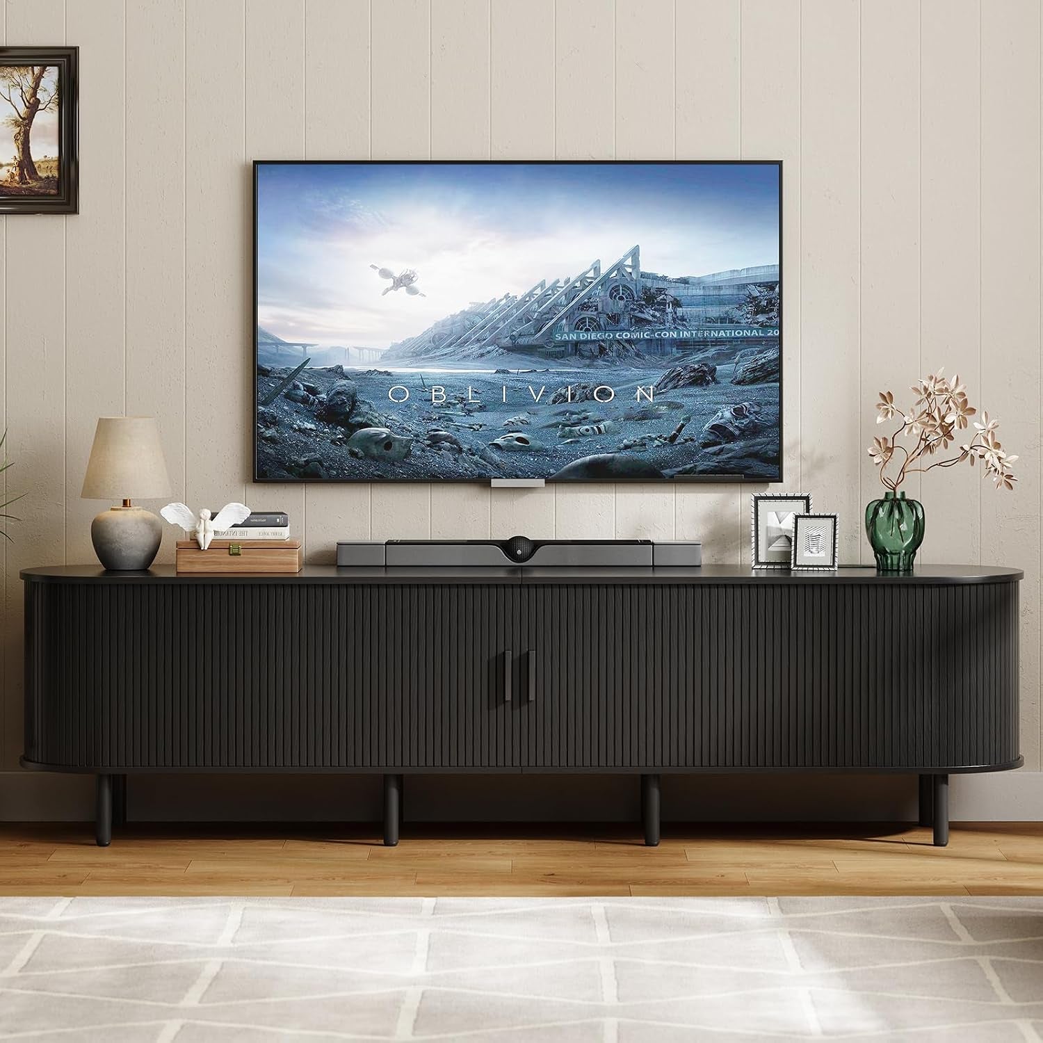 Matte black ribbed TV stand with a movie playing on the wall TV and framed photos and lamp on the top.