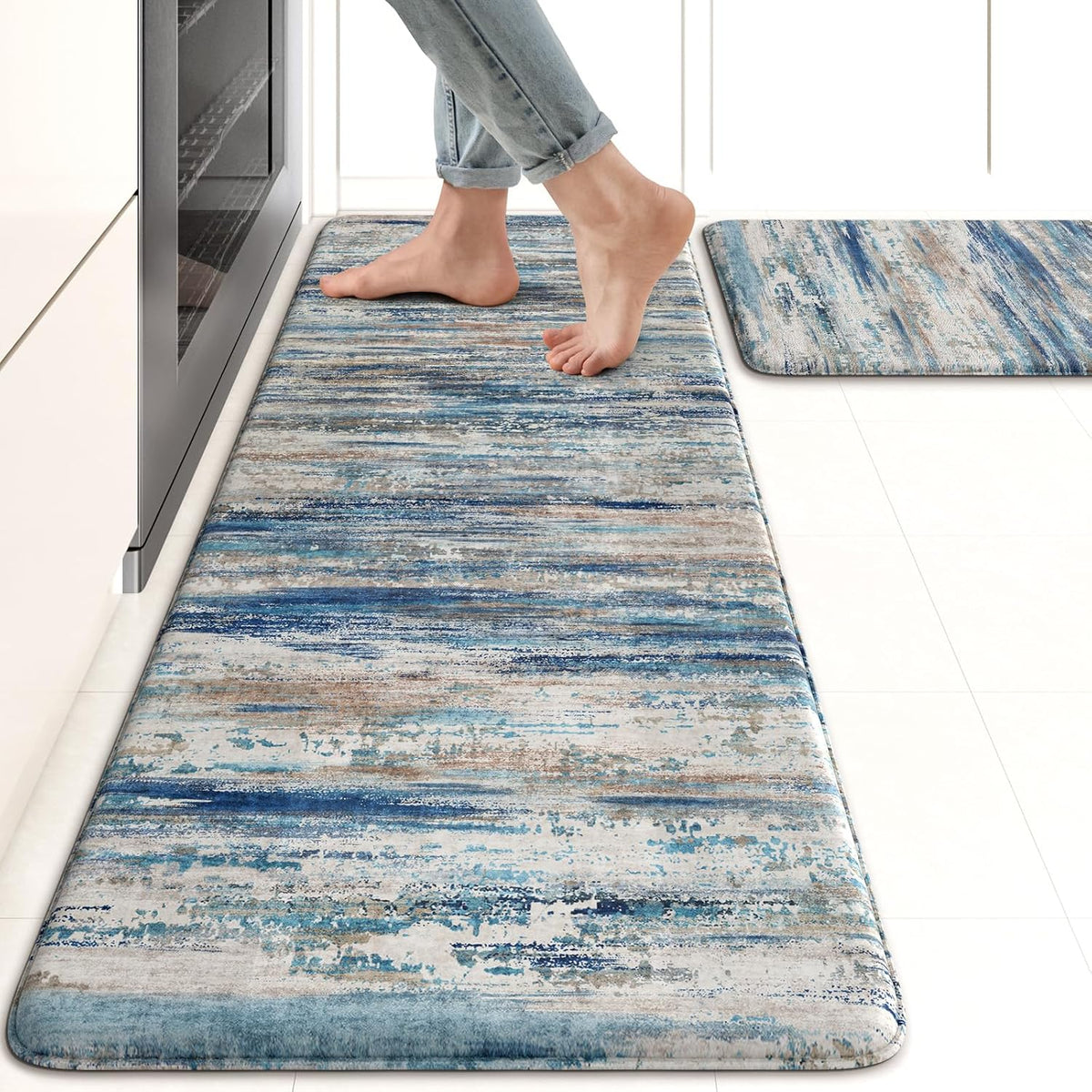 Blue and gray abstract runner rug in a bright kitchen with bare feet on the mat and a second rug nearby.