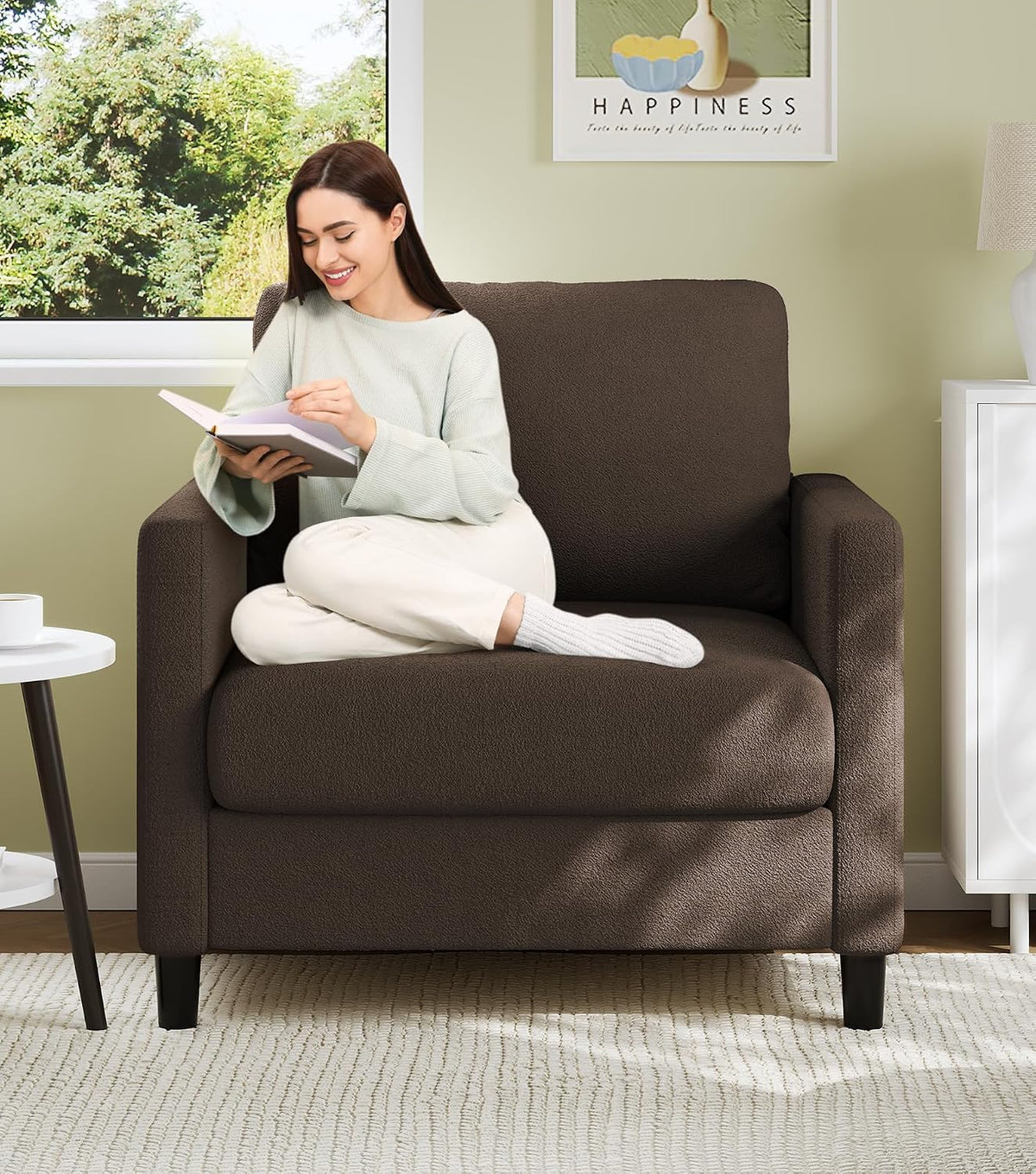 Dark brown small loveseat with a woman sitting cross-legged reading by a window