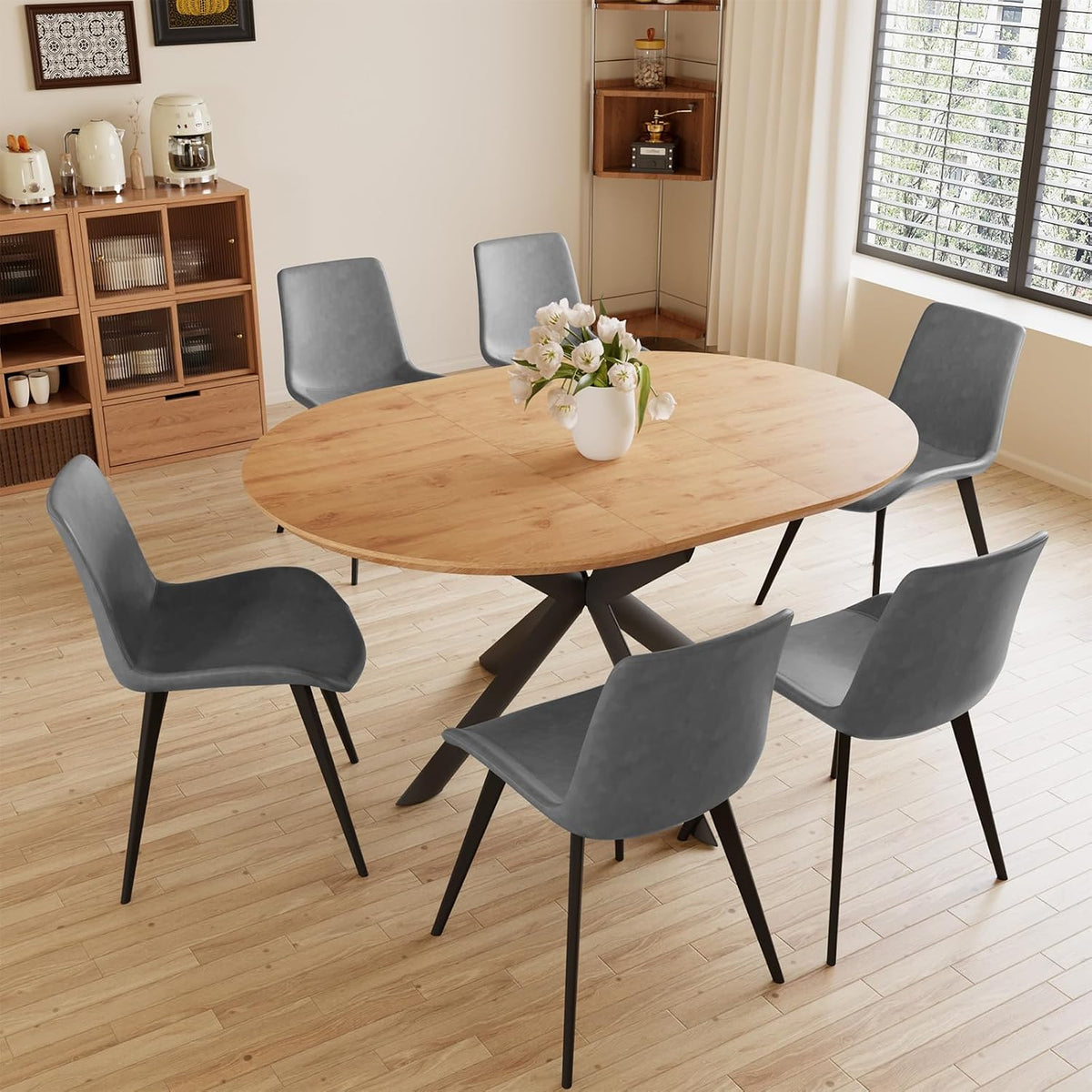 Light oak round table with six slate-gray chairs on a wood floor next to a large window