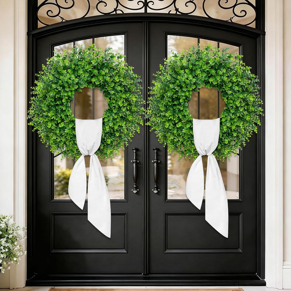 Pair of wreaths displayed on black double doors with white sashes