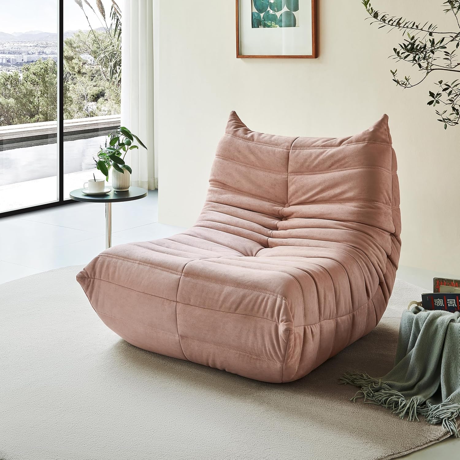 Blush-pink teddy-velvet lounge chair on a round rug beside a small side table and window.