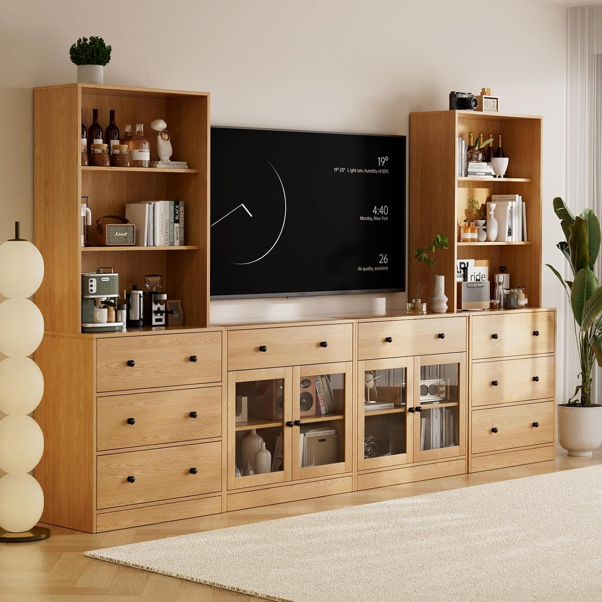 Wide living room view of a natural wood modular TV stand with tall bookcases flanking a mounted TV.