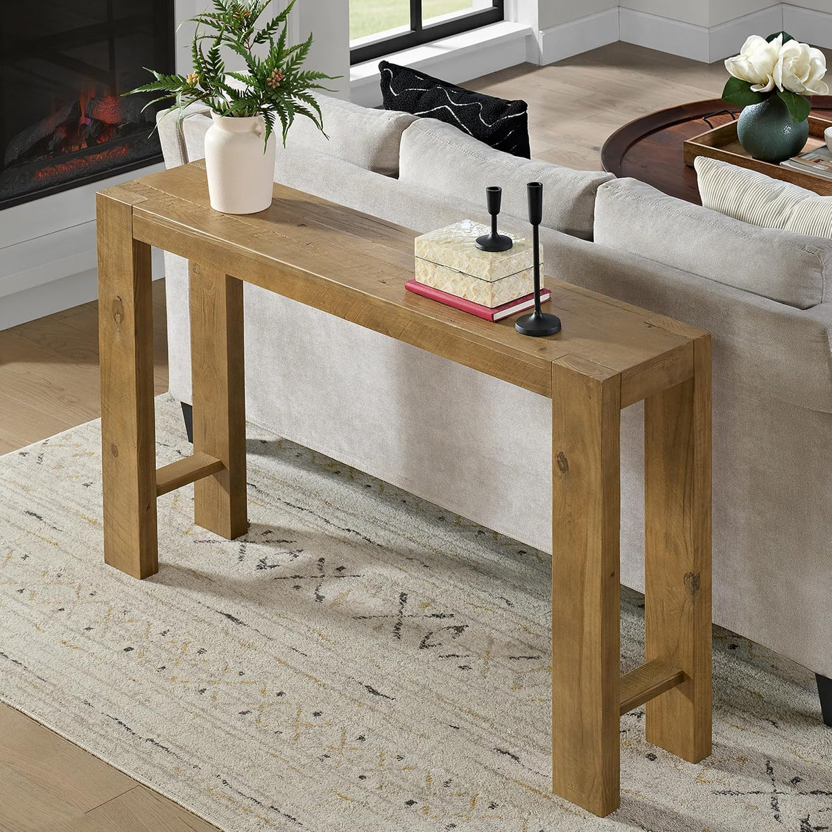 Console table placed behind a sofa in a living room scene with a potted plant and small decor on top.