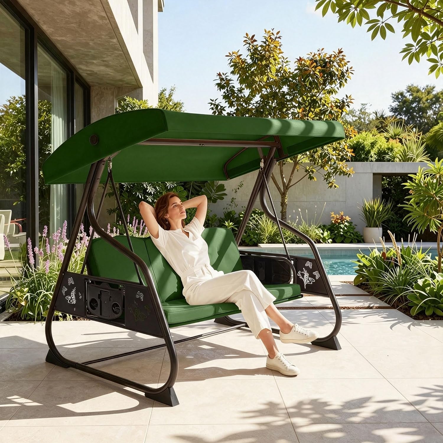 Woman reclining on a green-cushioned porch swing with canopy beside a pool and patio plants.