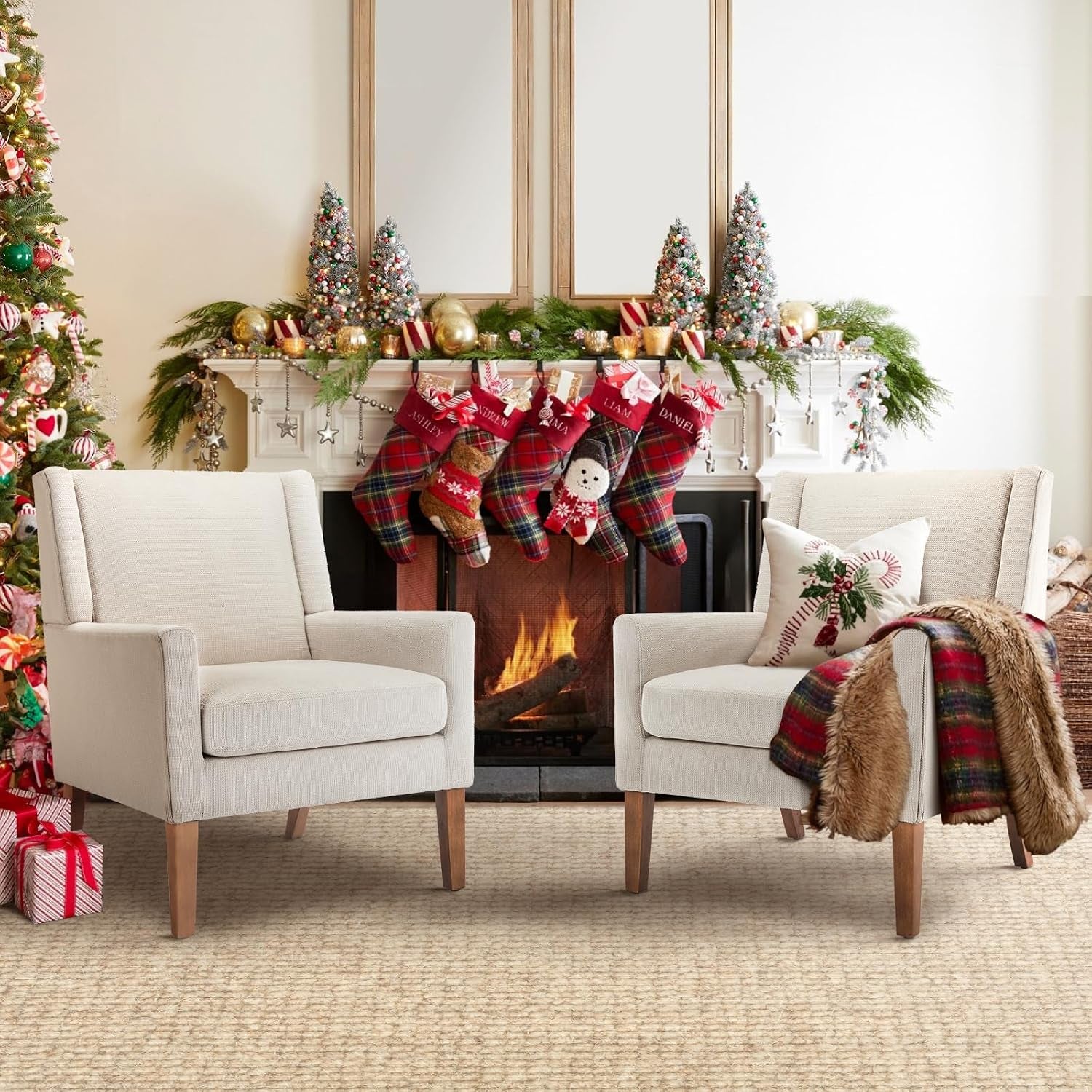 Two cream chenille wingback chairs with tapered wood legs flanking a fireplace decorated for Christmas.